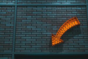 Decorative image: A lit-up orange arrow on a brick wall.