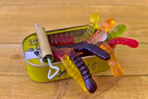 An open tin containing gummy worms.